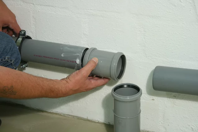 Person versucht eine verstopfte Toilette freizubekommen